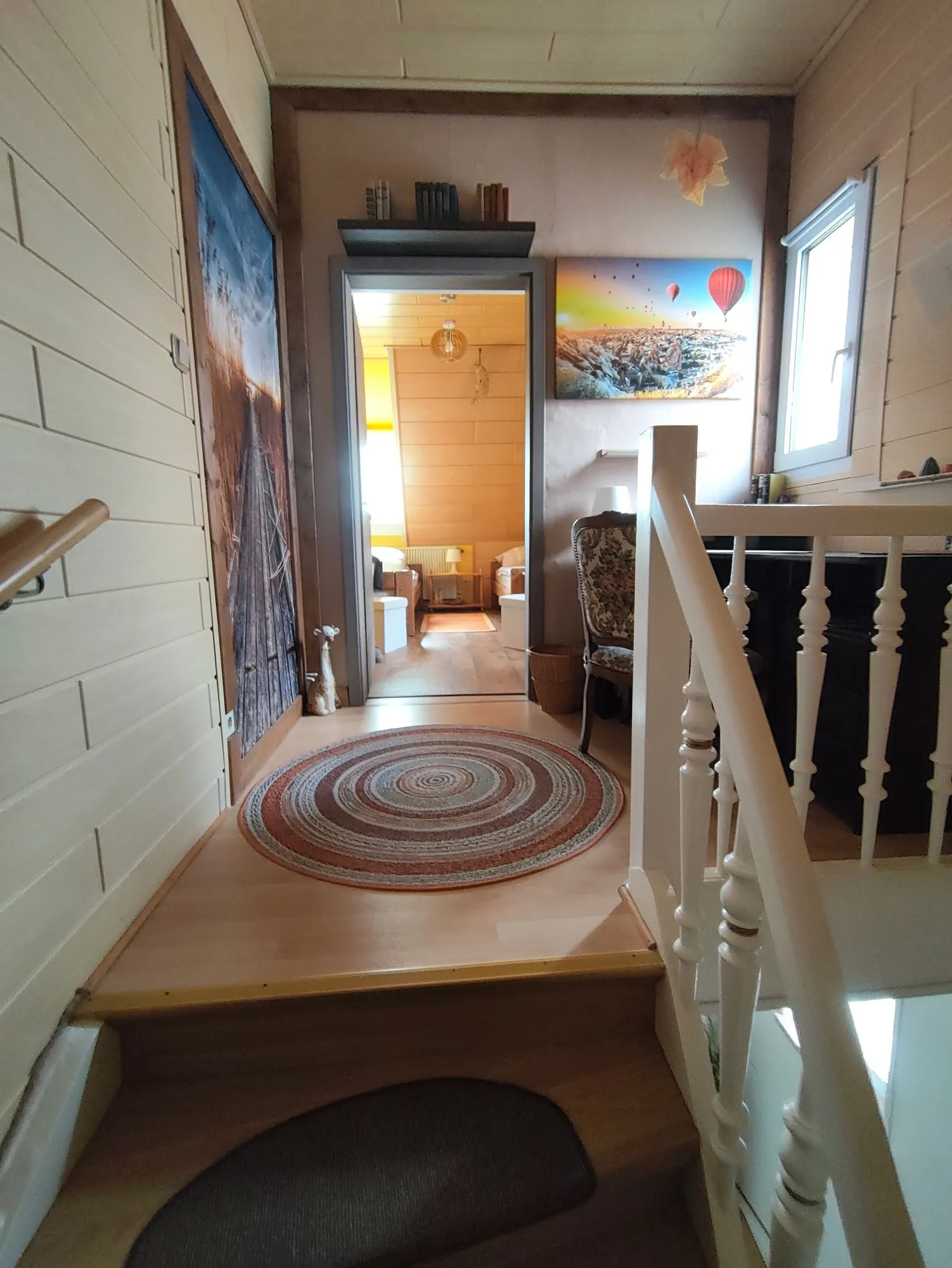 Oben angekommen: der Treppenabsatz mit rundem Teppich, vorn die offene Tür zu Zimmer 2.