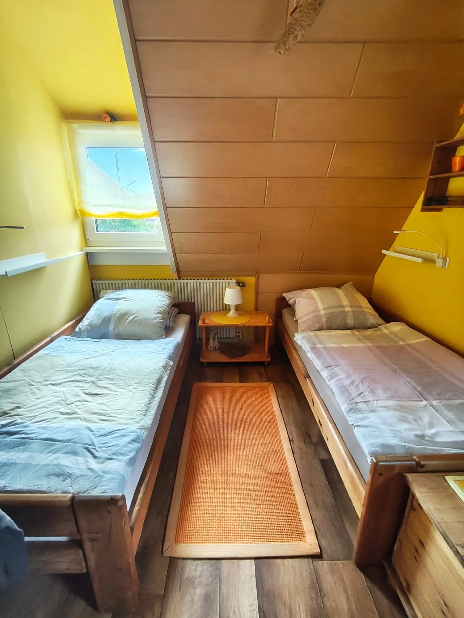 Zimmer 2 unter dem Dach: zwei Einzelbetten, gelbe Wände, Dachfenster.
